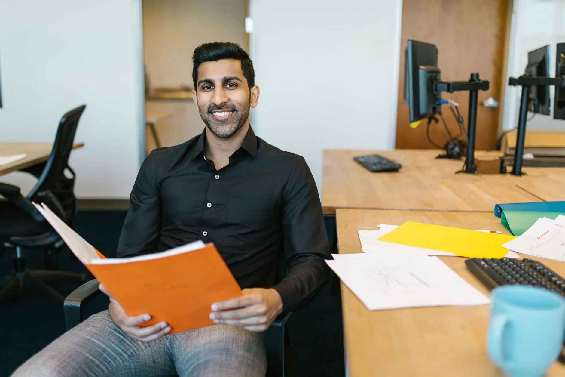 A smiling man reviewing a folder at his desk